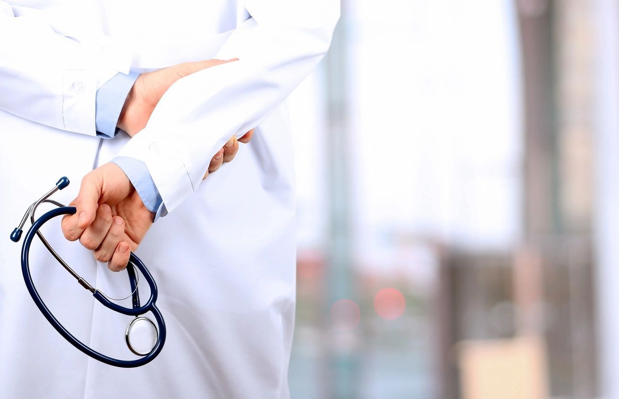 Healthcare professional holding a stethoscope in a bright clinical space